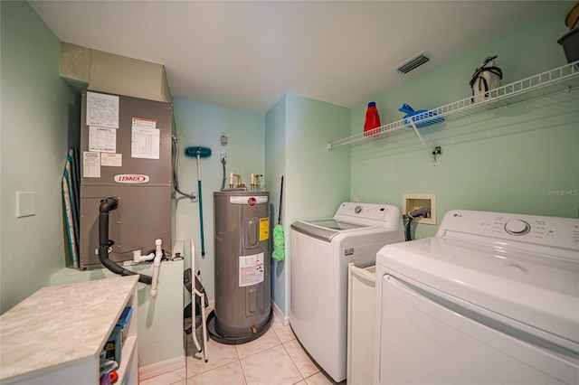 washroom with light tile patterned flooring, laundry area, separate washer and dryer, visible vents, and water heater