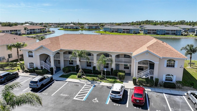 view of building exterior with uncovered parking, a residential view, and a water view