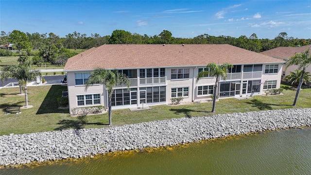 back of house with a yard, a water view, a sunroom, and stucco siding