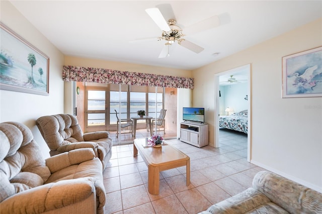 living area featuring light tile patterned floors, a ceiling fan, and baseboards