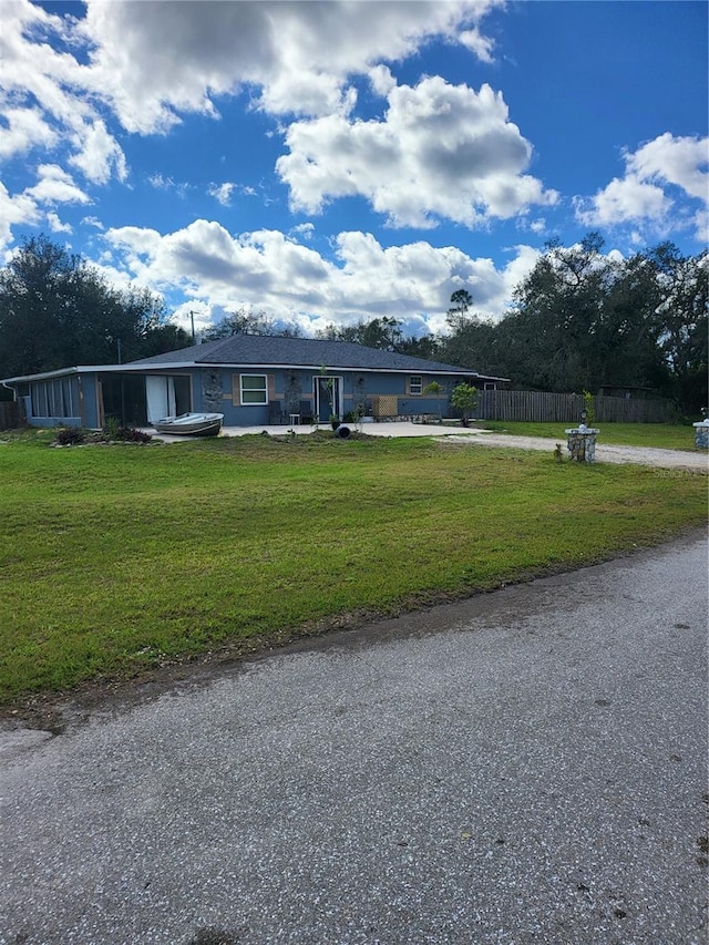 view of front facade featuring driveway, a front lawn, a patio, and fence