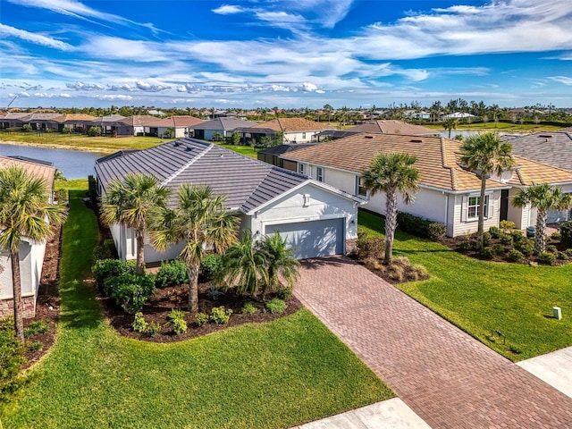 view of front of house with an attached garage, a water view, decorative driveway, a residential view, and a front yard