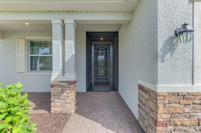 property entrance featuring stone siding and stucco siding