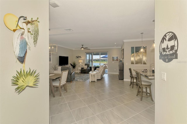 living area with ornamental molding, tile patterned flooring, baseboards, and a ceiling fan