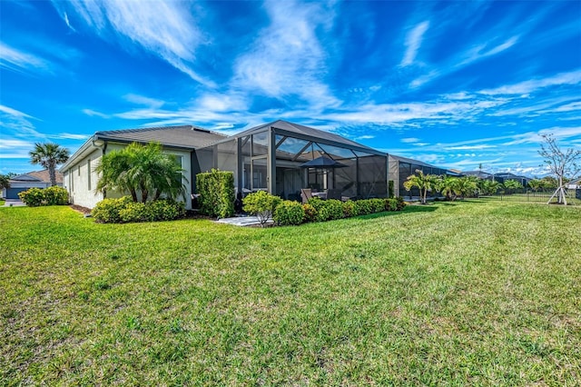 rear view of property featuring glass enclosure, a yard, and stucco siding