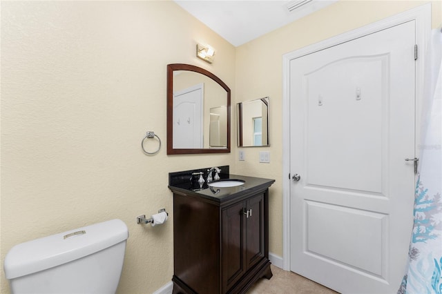 bathroom with toilet, vanity, and baseboards