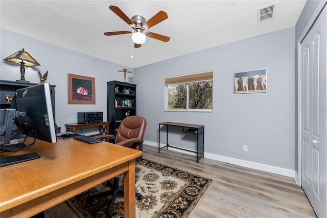 office area with baseboards, visible vents, a ceiling fan, a textured ceiling, and light wood-type flooring