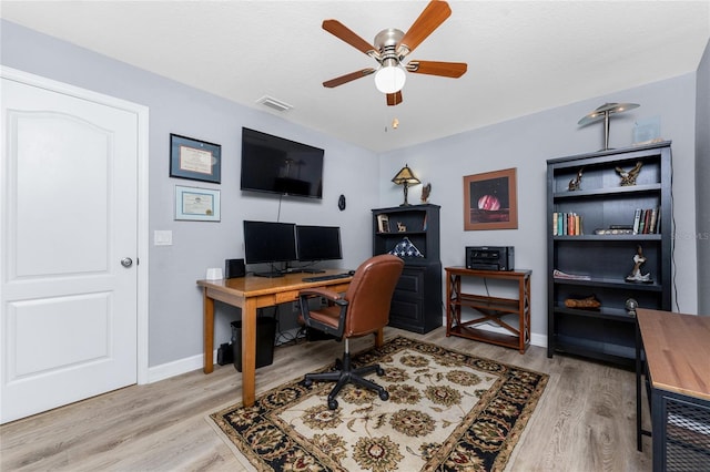 home office with light wood-style floors, visible vents, ceiling fan, and baseboards