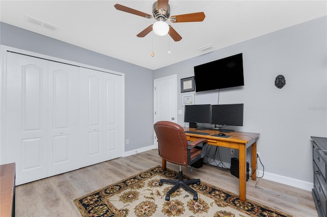 office featuring ceiling fan, light wood-type flooring, visible vents, and baseboards