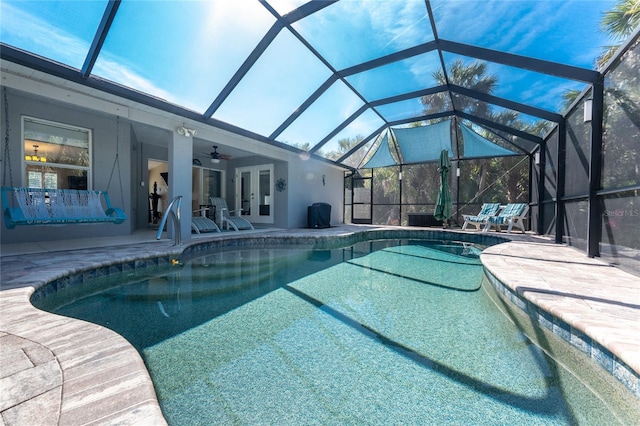 outdoor pool featuring glass enclosure, french doors, a patio area, and a ceiling fan