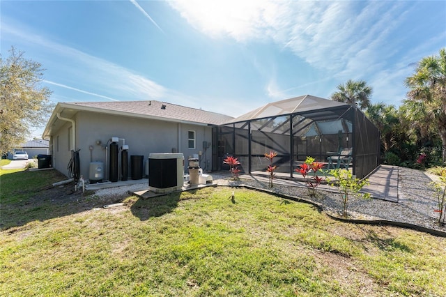 back of house featuring a patio, cooling unit, a lanai, a lawn, and stucco siding