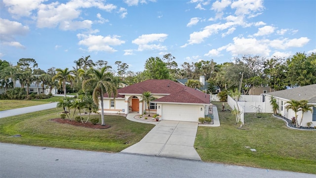 mediterranean / spanish home with stucco siding, fence, a garage, driveway, and a front lawn