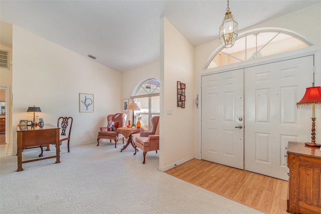 foyer with carpet floors, visible vents, an inviting chandelier, wood finished floors, and baseboards