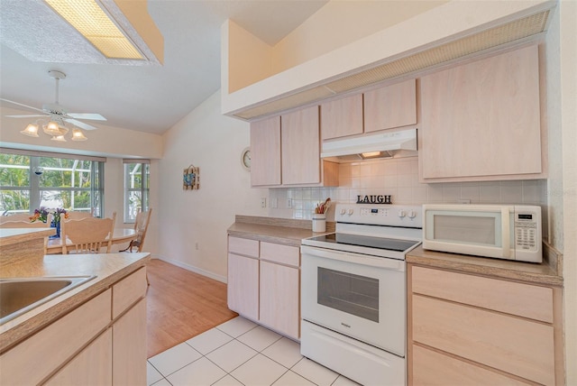 kitchen with light brown cabinetry, white appliances, decorative backsplash, and under cabinet range hood