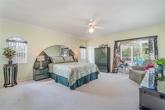 carpeted bedroom featuring access to exterior, baseboards, and a ceiling fan