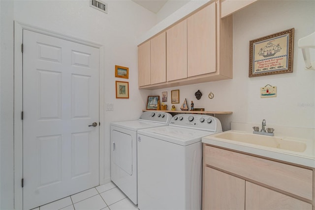 laundry area featuring light tile patterned floors, a sink, visible vents, cabinet space, and washing machine and clothes dryer