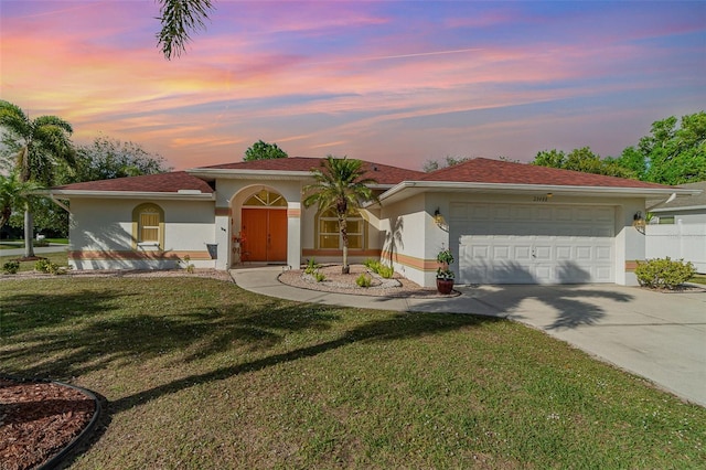 mediterranean / spanish-style home featuring driveway, an attached garage, a front lawn, and stucco siding