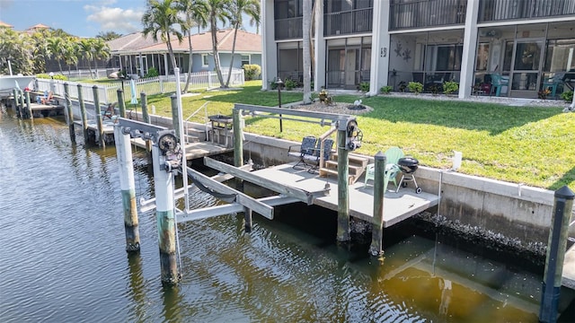 dock area with a water view, boat lift, and a yard