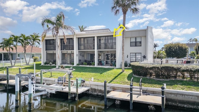 view of dock featuring a yard, a water view, boat lift, and fence