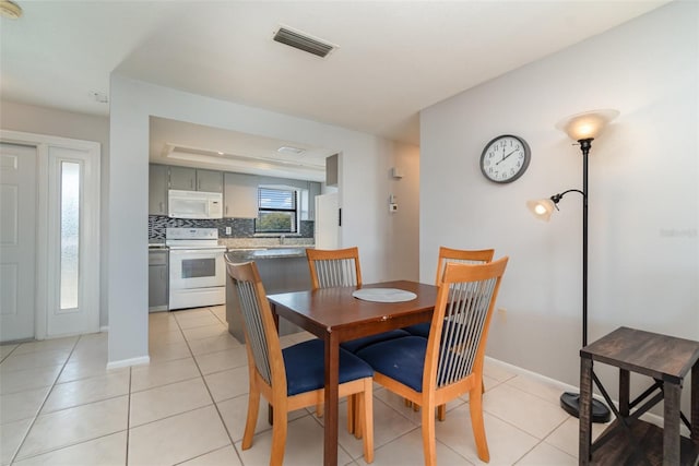 dining room featuring light tile patterned floors, visible vents, and baseboards