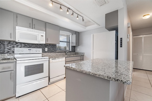 kitchen with gray cabinets, a tray ceiling, white appliances, and light tile patterned floors