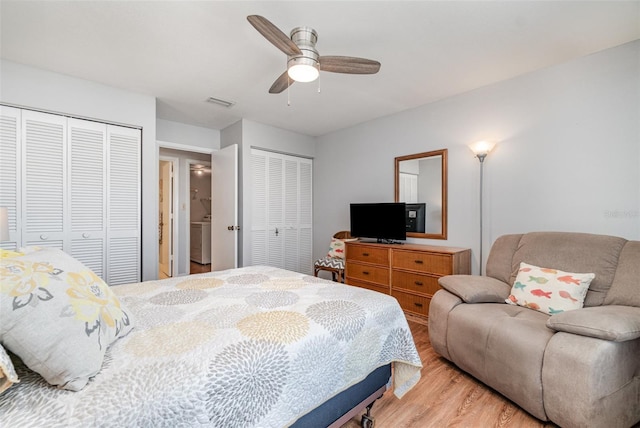 bedroom featuring multiple closets, visible vents, ceiling fan, and light wood finished floors