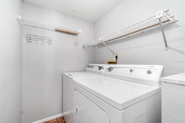 laundry room with laundry area, washing machine and dryer, and baseboards