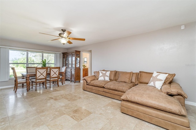 living area featuring a ceiling fan and baseboards