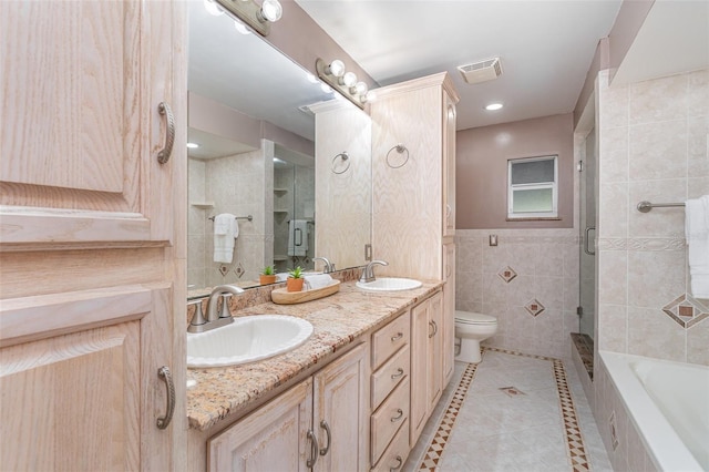 full bath with toilet, tile walls, visible vents, and a sink