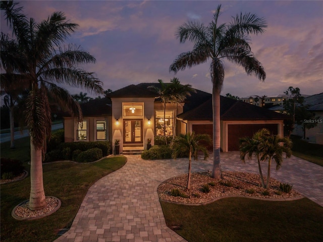 view of front of house featuring a garage, a yard, decorative driveway, and french doors