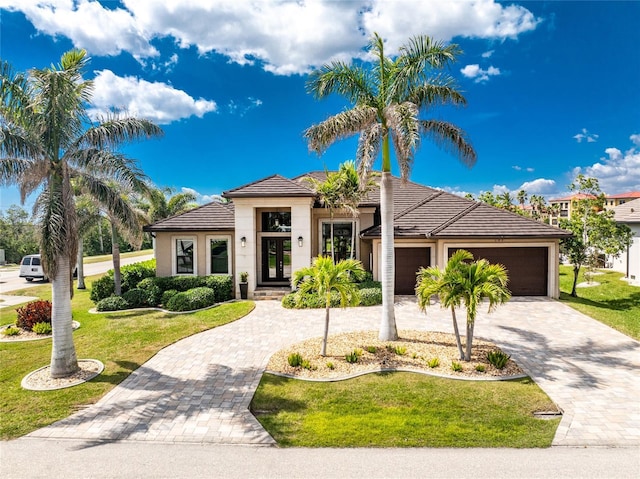 prairie-style home with a front lawn, decorative driveway, an attached garage, and a tile roof