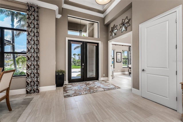 entryway featuring light wood finished floors, a high ceiling, baseboards, and french doors