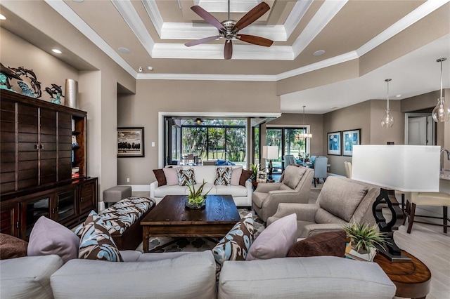 living room with crown molding, a raised ceiling, a high ceiling, baseboards, and ceiling fan with notable chandelier