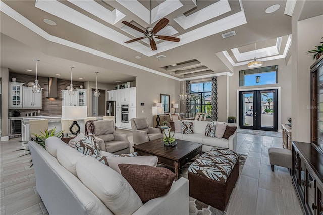 living room featuring a skylight, visible vents, a raised ceiling, ornamental molding, and french doors