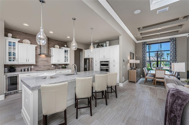 kitchen with wine cooler, tasteful backsplash, appliances with stainless steel finishes, a sink, and a kitchen breakfast bar