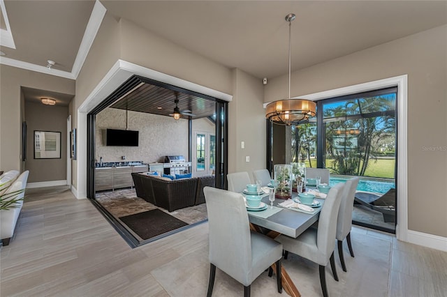 dining area featuring a chandelier, crown molding, light wood-style floors, and baseboards