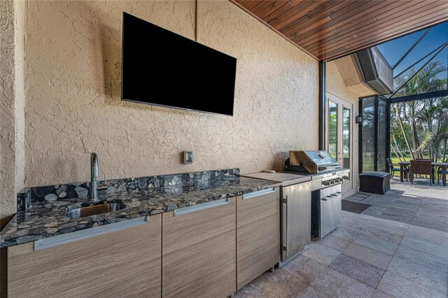 view of patio with an outdoor kitchen, a lanai, area for grilling, a sink, and outdoor dining space