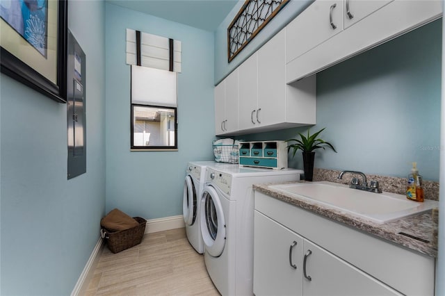 laundry area with cabinet space, a sink, light wood-type flooring, independent washer and dryer, and baseboards