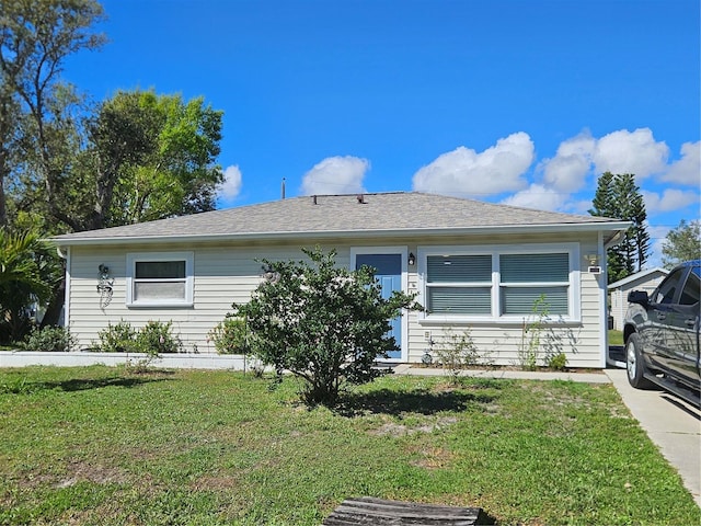 ranch-style home with a shingled roof and a front yard