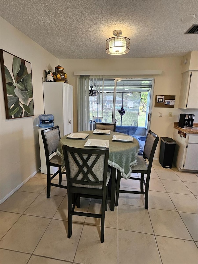 dining space featuring light tile patterned floors, a textured ceiling, visible vents, and baseboards