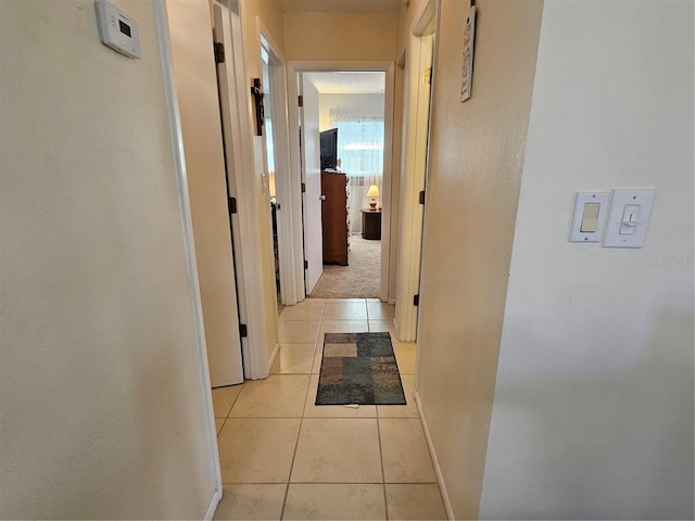 hallway with light tile patterned flooring and baseboards