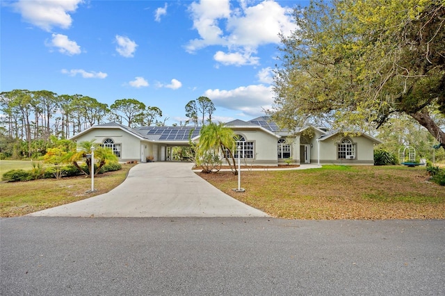 ranch-style house featuring an attached carport, a front yard, concrete driveway, and stucco siding