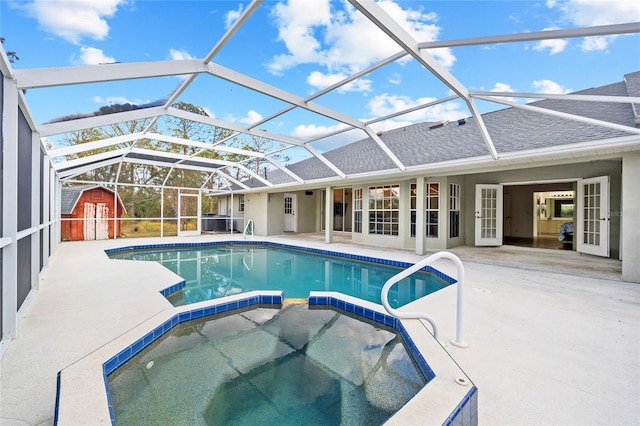 view of swimming pool with an outbuilding, a pool with connected hot tub, a shed, a lanai, and a patio area