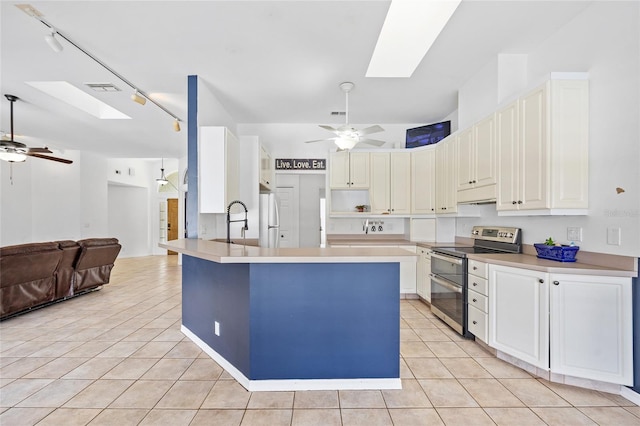 kitchen with a ceiling fan, a skylight, light tile patterned floors, and double oven range