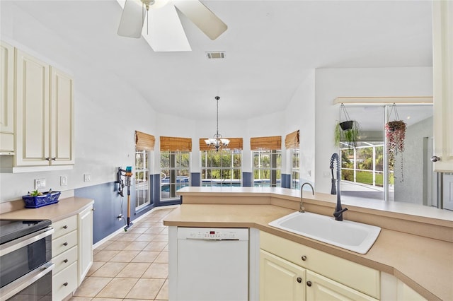 kitchen featuring a sink, double oven range, cream cabinets, and white dishwasher