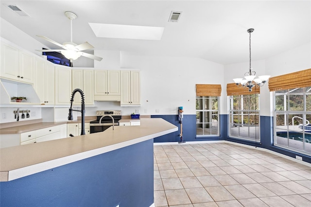 kitchen featuring visible vents, vaulted ceiling with skylight, light countertops, and electric stove