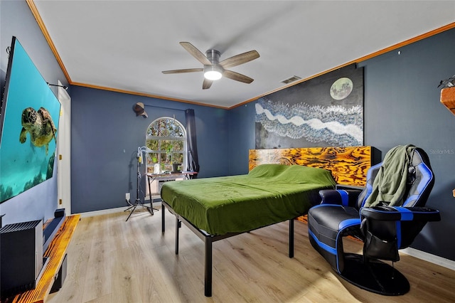 bedroom with crown molding, wood finished floors, baseboards, and visible vents