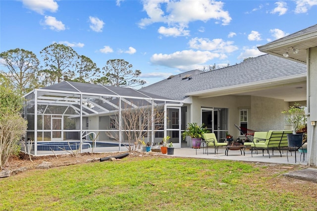 rear view of house with glass enclosure, roof with shingles, a yard, stucco siding, and a patio area