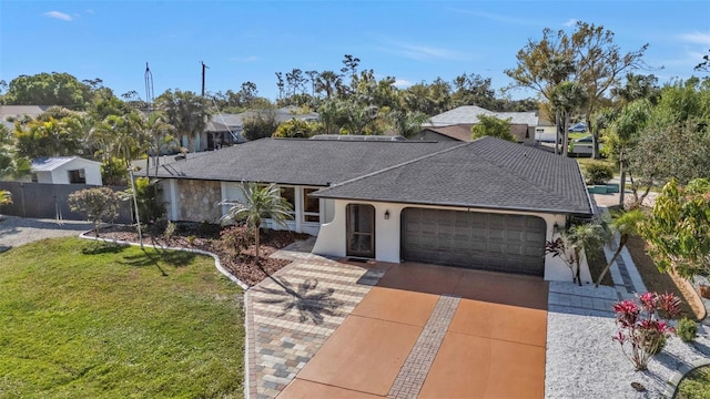 view of front of house with stucco siding, a shingled roof, a front yard, a garage, and driveway