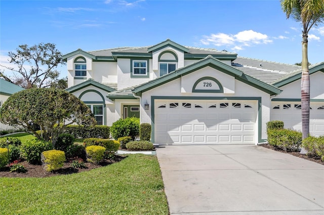 traditional-style home with stucco siding, driveway, a tile roof, and a garage